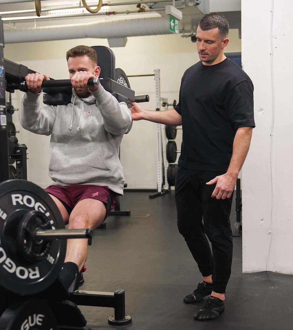 Romain helping a client with a pendulum squat.