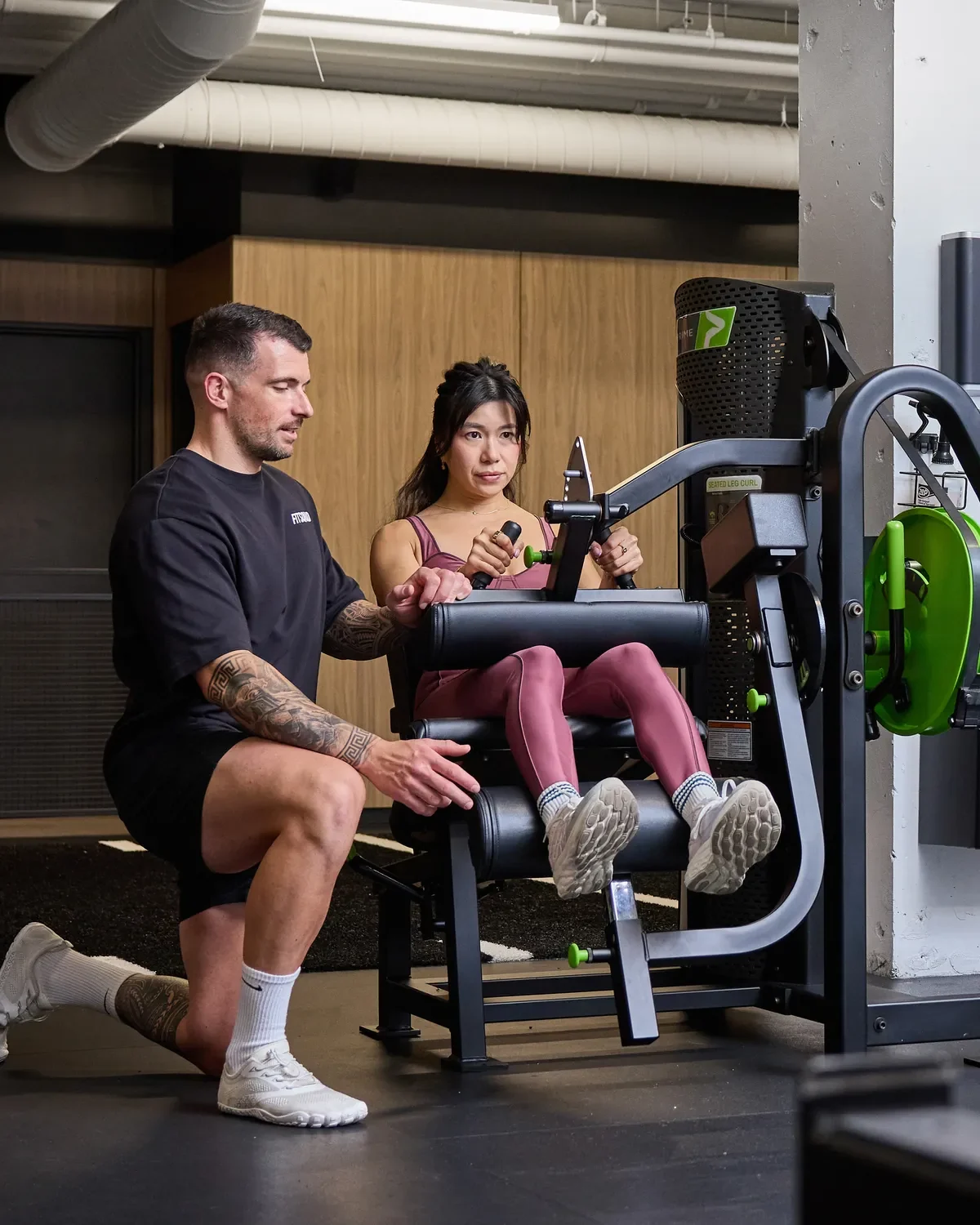Romain coaching a female client on a leg curl at Fit Squad